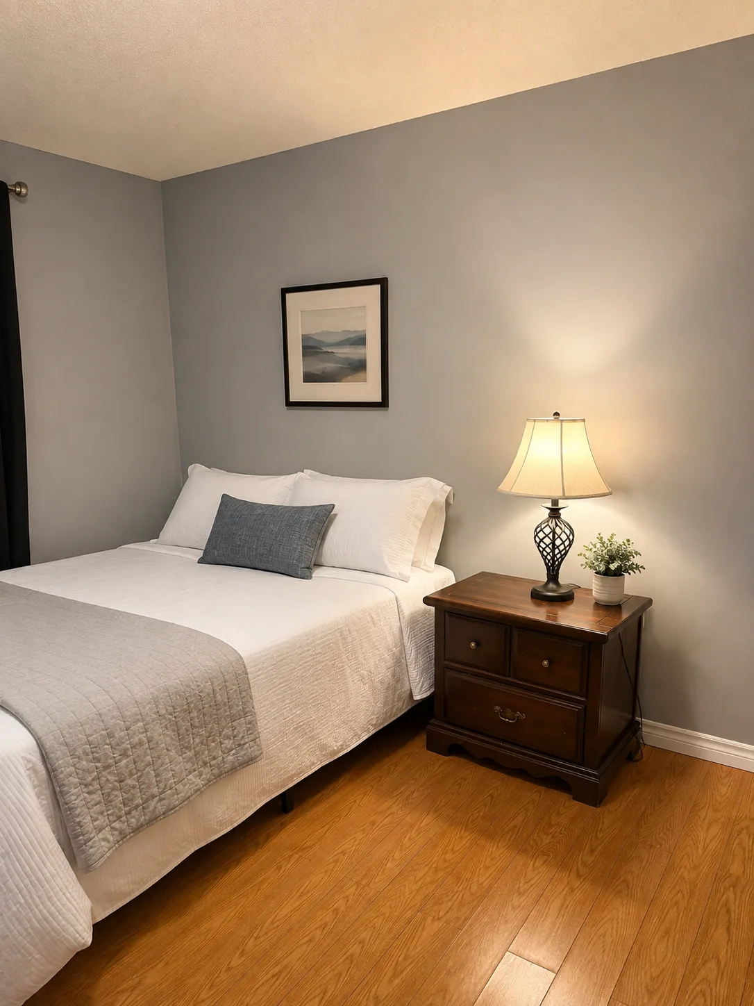Second furnished bedroom with nightstand and warm lamp